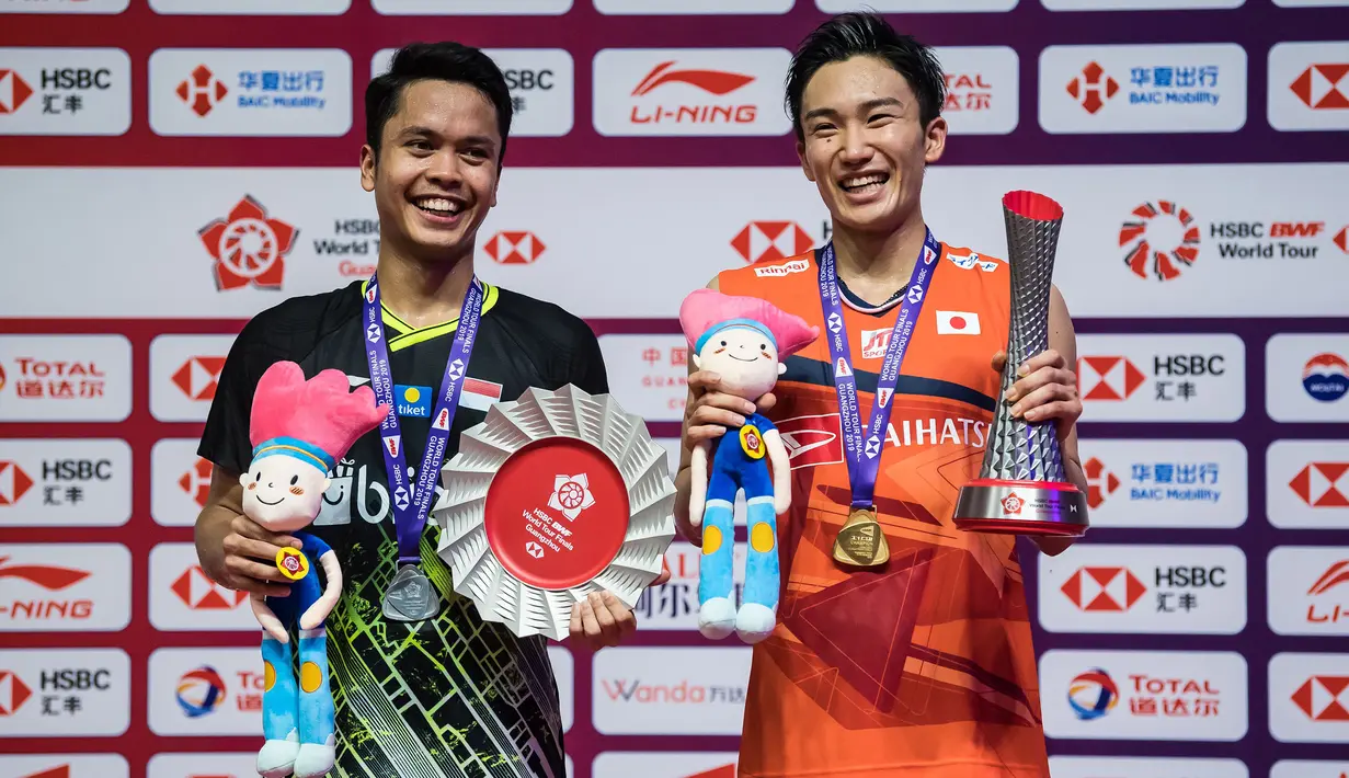 Tunggal putra Indonesia, Anthony Ginting, naik podium bersama tunggal Jepang, Kento Momota, pada BWF World Tour 2019 di Tianhe Gymnasium, Guangzhou, Minggu (15/12). Ginting kalah 21-17, 17-21 dan 14-21 dari Momota. (AFP/STR)