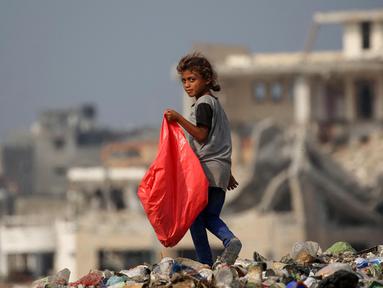 Seorang anak pengungsi Palestina membawa plastik besar untuk diisi dengan barang-barang yang ditemukan di tumpukan sampah, di kamp pengungsi al-Bureij di Jalur Gaza tengah pada 10 November 2024. (Eyad BABA/AFP)