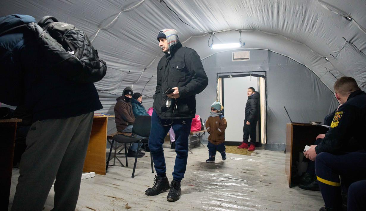 Jutaan warga kini terpaksa bertahan di tengah suhu musim dingin yang menusuk, tanpa pasokan listrik, air, dan pemanas yang memadai. Tampak dalam foto, warga menghangatkan diri dan mengisi daya baterai mereka di salah satu tenda yang didirikan oleh layanan darurat menyusul serangan udara rutin Rusia terhadap fasilitas energi negara itu di tengah musim dingin, Kyiv, Ukraina, Selasa 13 Januari 2026. (AP Photo/Efrem Lukatsky)