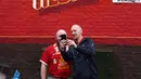 Dua pendukung Liverpool berfoto di depan tembok yang bertuliskan "You'll Never Walk Alone" sebelum laga lanjutan Liga Inggris 2024/2025 melawan Brentford di Anfield, Liverpool, Inggris, Minggu (25/08/2024) malam WIB. (AFP/Darren Stapless)