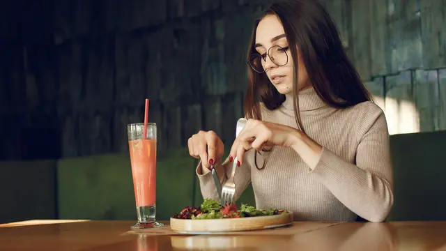 Seorang perempuan sedang menikmati sepiring salad dan jus buah (Foto Dok: Freepik/prostooleh)