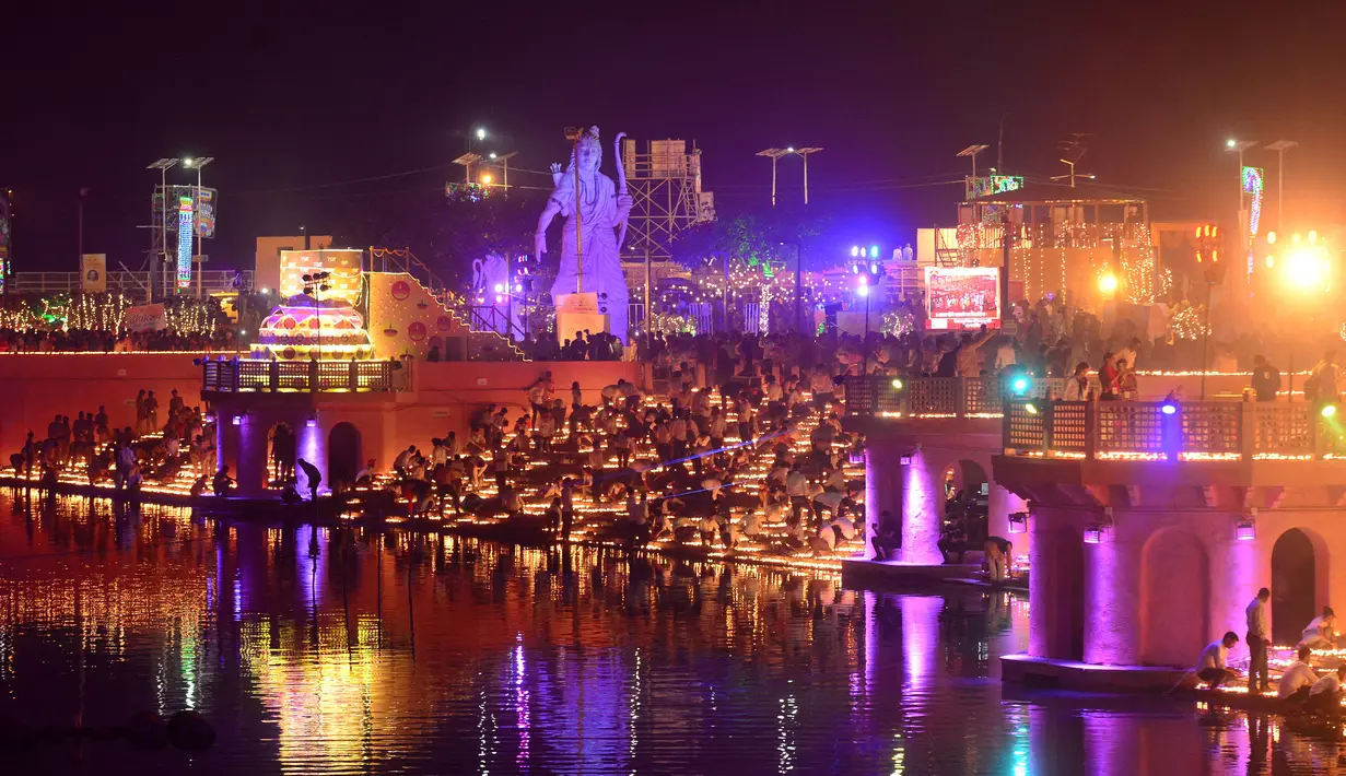 Orang-orang India menyalakan lampu dari tanah liat pada festival Diwali di tepi Sungai Sarayu, Ayodhya, Selasa (6/11). Kota di utara India itu memecahkan rekor dunia Guinness setelah menyalakan 300.150 lampu selama 45 menit. (SANJAY KANOJIA/AFP)