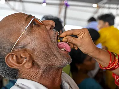 Seorang pasien menelan ikan murrel hidup dengan ramuan obat asma yang diberikan oleh keluarga Bathini Goud, di tempat pameran di Hyderabad, India, Jumat (9/6/2023). (Photo by Noah SEELAM / AFP)