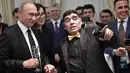 Presiden Rusia Vladimir Putin (kiri) berbincang dengan legenda sepak bola Argentina, Diego Maradona saat menghadiri undian Piala Dunia 2018 di Moskow, Rusia (1/12). (AFP Photo/Sputnik/Alexey Nikolsky)