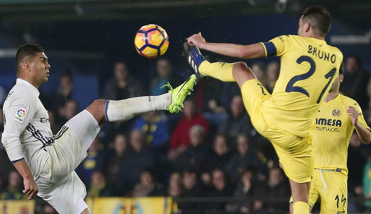 Gelandang Real Madrid, Casemiro, berebut bola dengan gelandang Villarreal, Bruno Soriano. Bermain tandang, Real madrid lebih menguasai jalannya laga berdasar data statistik penguasaan bola mereka mencapai 54 persen. (EPA/Miguel Angel Polo)