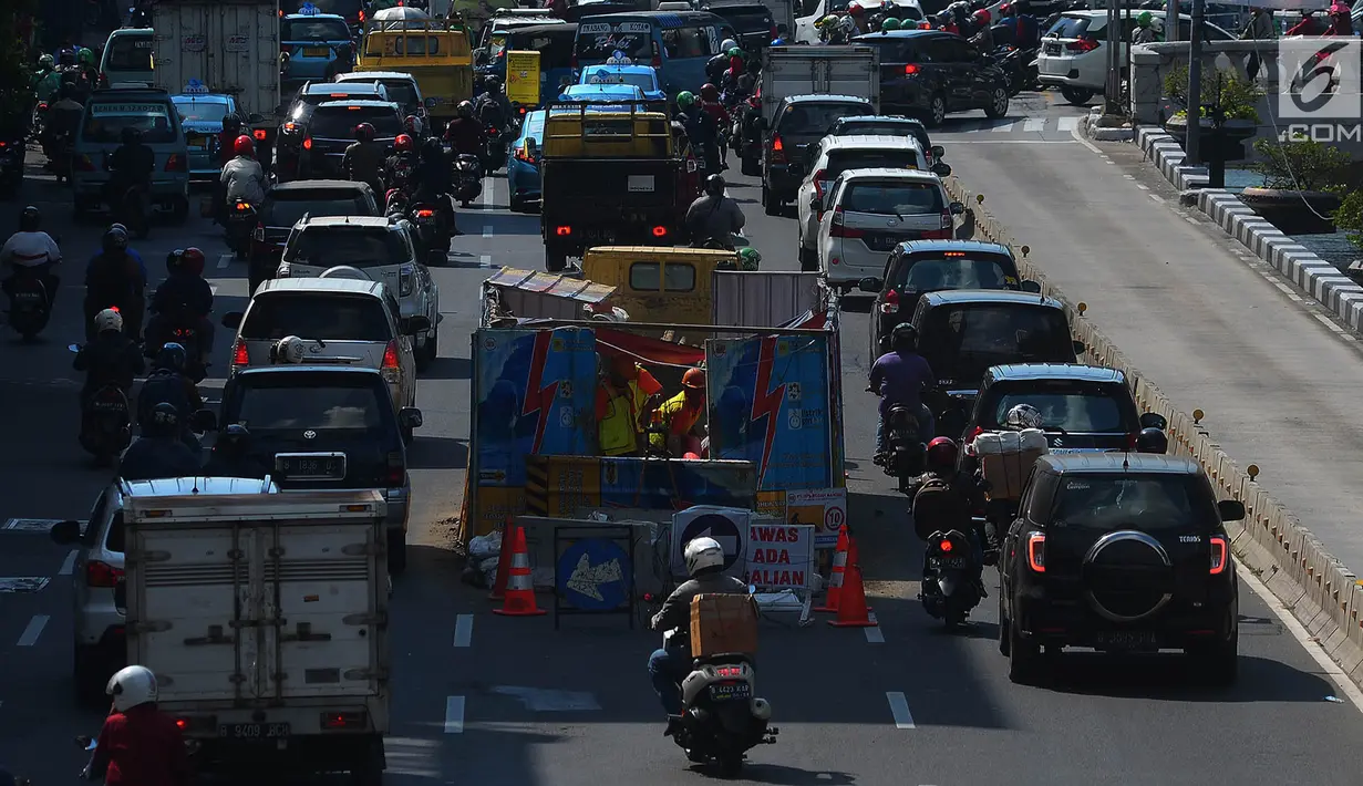 Sejumlah kendaraan melintas di dekat galian kabel yang berada di tengah jalan Gajah Mada, Jakarta, Sabtu (12/5). Galian kabel instalasi listrik yang berada di tengah jalan ini membuat arus lalu lintas sedikit tersendat. (Merdeka.com/Imam Buhori)