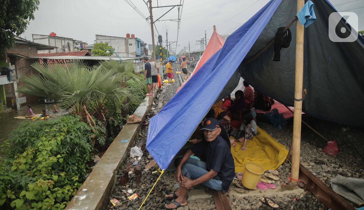 Pengungsi banjir beristirahat dalam tenda yang didirikan di jalur rel kereta commuterline Tangerang-Duri di Kembangan Baru, Jakarta, Jumat (3/1/2020). Jalur rel yang nonaktif sementara karena banjir dimanfaatkan warga untuk mendirikan tenda darurat. (Liputan6.com/Faizal Fanani)