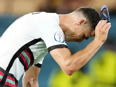 Bintang Timnas Portugal, Cristiano Ronaldo, tak mampu menutupi kekecewaan usai timnya didepak Belgia pada babak 16 besar Euro 2020. (AP/Thanassis Stavrakis, Pool)