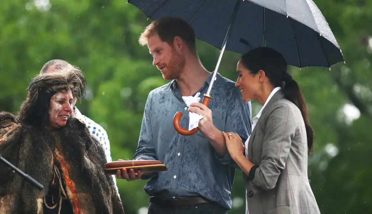 Pangeran Harry dan Meghan Markle berbincang dengan penari aborigin saat mengunjungi Victoria Park, Dubbo, Australia, Rabu (17/10). Keduanya diagendakan tur ke Australia dan Pasifik Selatan selama 16 hari. (Ian Vogler/Pool via AP)