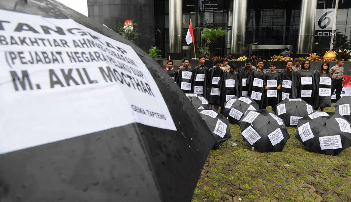 Sejumlah aktivis dari Gema Tapteng berbaris sambil menjejerkan payung hitam saat melakukan aksi unjuk rasa di depan gedung KPK, Jakarta, Kamis (26/4). (Merdeka.com/Dwi Narwoko)