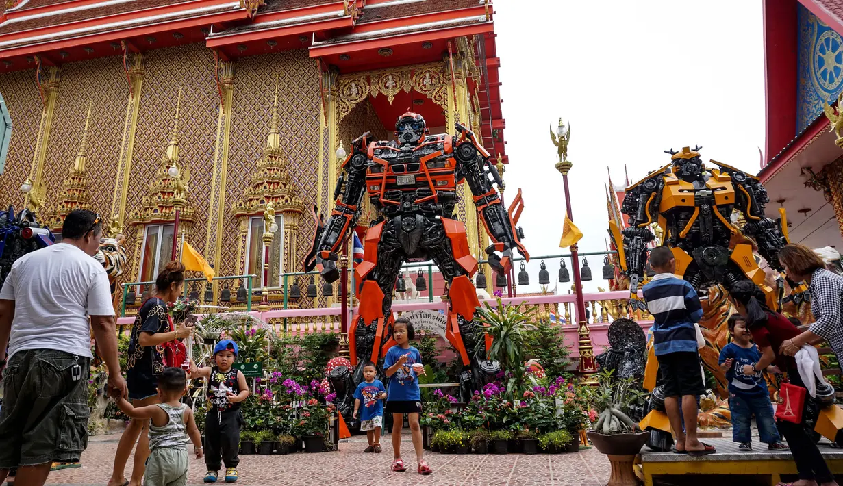 Suasana di depan kuil Buddha Wat Tha Kien yang menghadirkan patung logam raksasa yang terinspirasi oleh 'Transformers' di Nonthaburi, Thailand (18/6). Patung karya Ban Hun Lek dihadirkan untuk menarik pengunjung. (AFP Photo/Lillian Suwanrumpha)