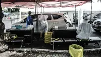 Petugas kesehatan melakukan tes usap PCR drive thru kepada pengguna kendaraan di halaman Rumah Sakit Pertamina Jakarta (RSPJ), Rabu (6/1/2021). RSPJ menyediakan layanan tes usap PCR mandiri secara drive thru guna melacak sekaligus memutus penyebaran Covid-19. (merdeka.com/Iqbal Nugroho)