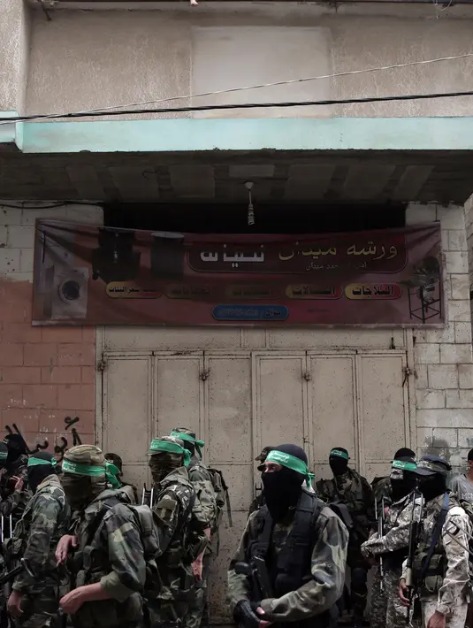 Tentara Hamas mengenakan topeng dan membawa senjata berjaga saat iring-iringan jenazah rekan mereka yang tewas di Deir el-Balah, Jalur Gaza (6/5). (AP/Khalil Hamra)