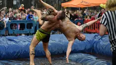 Pegulat membanting lawannya saat mengikuti World Gravy Wrestling Championships ke-10 di Rose 'n' Bowl Pub di Inggris (28/8). Dalam pertandingan gulat ini, peserta mengenakan pakain unik saat bertanding. (AFP Photo/Oli Scarff)