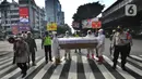 Petugas Gabungan membawa peti mati di hadapan pengendara bermotor di perempatan Fatmawati, Jakarta Selatan, Kamis (3/9/2020). Kegiatan tersebut dalam rangka sosialisasi kewaspadaan dan kesadaran warga ibukota di tengah pandemi corona yang dapat menyebabkan kematian. (merdeka.com/Arie Basuki)