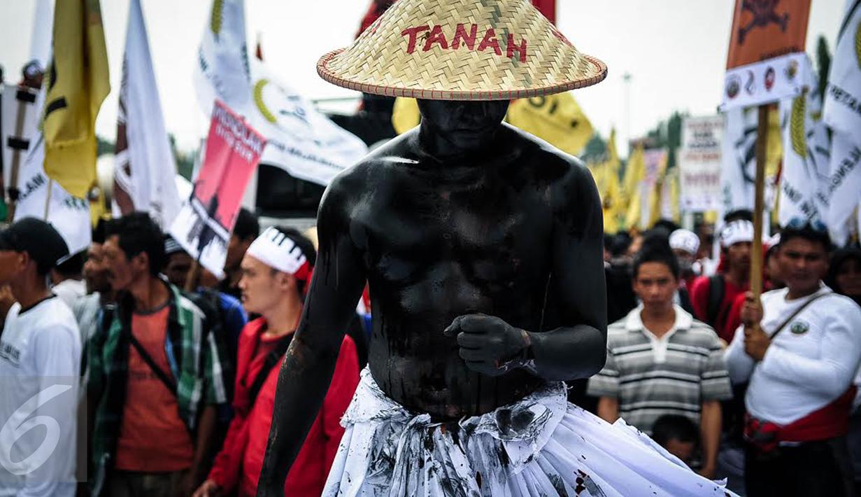 Seorang massa petani dari berbagai provinsi melakukan aksi teatrikal saat menggelar demonstrasi di kawasan Medan Merdeka, Jakarta, Selasa (27/9). Aksi menyuarakan aspirasi petani itu digelar dalam rangka Hari Tani Nasional. (Liputan6.com/Faizal Fanani)