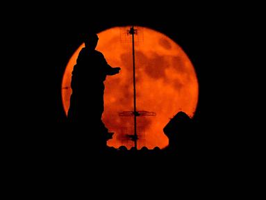 Bulan purnama, yang dikenal sebagai 'Bulan Stroberi', muncul di atas Fori Imperiali di pusat kota Roma, Italia, 11 Juni 2025. (Tiziana FABI/AFP)