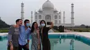Turis berfoto dengan latar belakang Taj Mahal di Agra, India pada Senin (21/9/2020). Taj Mahal kembali dibuka untuk umum hari ini, Senin (21/9), saat negara dengan 1,3 miliar orang itu telah mencatat lebih dari 5,4 juta kasus Covid-19. (Sajjad HUSSAIN/AFP)