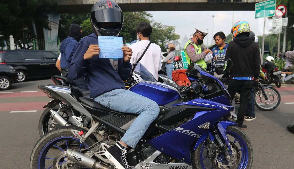 Pengendara motor menunjukkan surat tilang saat razia knalpot bising di Monas, Jakarta, Minggu (7/3/2021). Direktorat Lalu Lintas Polda Metro Jaya mengeluarkan kebijakan larangan kendaraan bermotor berknalpot bising melintas di kawasan Monas pada hari Sabtu dan Minggu. (Liputan6.com/Herman Zakharia)