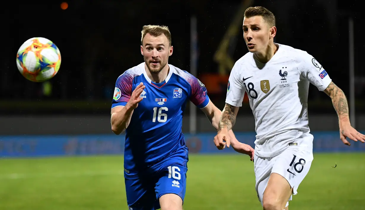 Gelandang Islandia, Runar Mar Sigurjonsson berebut bola dengan pemain belakang Prancis, Lucas Digne dalam laga lanjutan Grup H Kualifikasi Piala Eropa 2020 di Stadion Laugardalsvollur, Reykjavik, Jumat (11/10/2019). Timnas Prancis harus susah payah mengalahkan Islandia 1-0. (Jonathan NACKSTRAND/AFP)