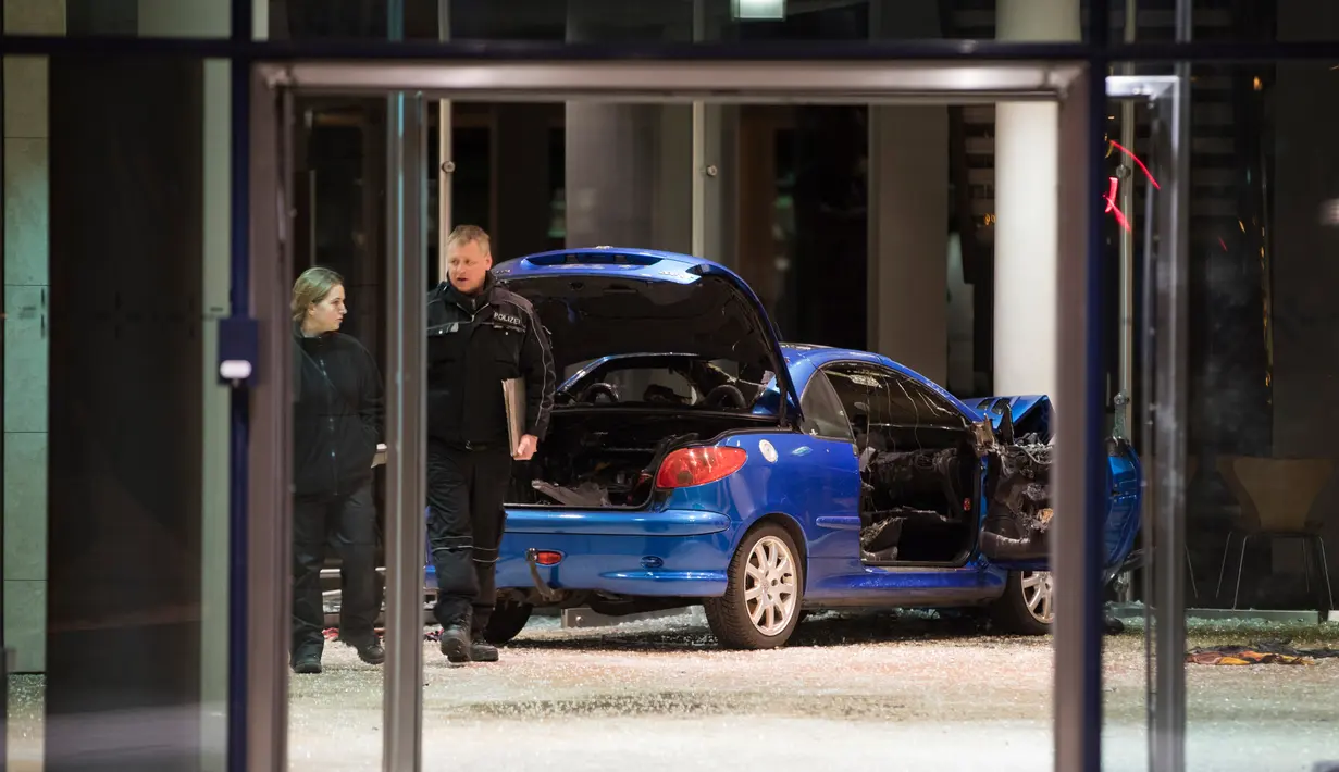 Polisi memeriksa kerusakan di lobi kantor Partai Sosial Demokratik Jerman (SPD) setelah sebuah mobili menabrakan gedung dengan sengaja di Berlin (25/12). Pelaku pria berusia 58 tahun menabrakan diri pada malam Natal. (AFP PHOTO / Ganjil Andersen)