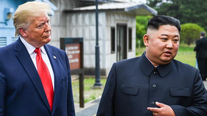 Pemimpin Korea Utara, Kim Jong-un berbincang dengan Presiden AS, Donald Trump di zona demiliterisasi Korea (DMZ), Desa Panmunjom pada Minggu (30/6/2019).  Pertemuan keduanya berawal ketika Trump menuliskan undangan pertemuan dengan Kim melalui Twitter. (Brendan Smialowski/AFP)