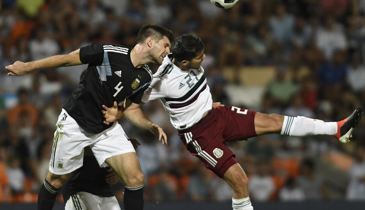 Bek Argentina Walter Kannemann saat berduel dengan pemain Meksiko, Henry Martin Meksiko pada laga persahabatan yang berlangsung di stadion Malvinas, Rabu (21/11). Argentina menang 2-0 atas Meksiko (AFP/Andres Larrovere)