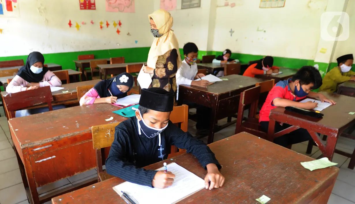 Guru mengawasi murid kelas V saat menjalani ujian Penilaian Akhir Semester (PAS) tahun pelajaran 2020/2021 di Madrasah Ibtidayah (MI) Assu'ada di Pancoran Mas, Depok, Jawa Barat, Selasa (1/12/2020). Ujian dilaksanakan dengan menerapkan protokol kesehatan dalam kelas. (merdeka.com/Arie Basuki)