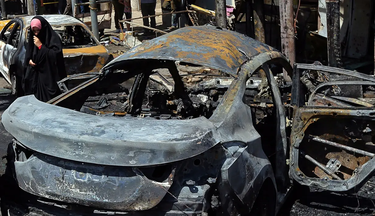 Bangkai mobil yang hangus terbakar usai terkena ledakan bom di Baghdad, Irak (30/5). Dalam insiden ini, pihak radikal ISIS mengklaim bahwa serangan bom bunuh diri tersebut dilakukan oleh kelompok mereka. (AP Photo / Karim Kadim)