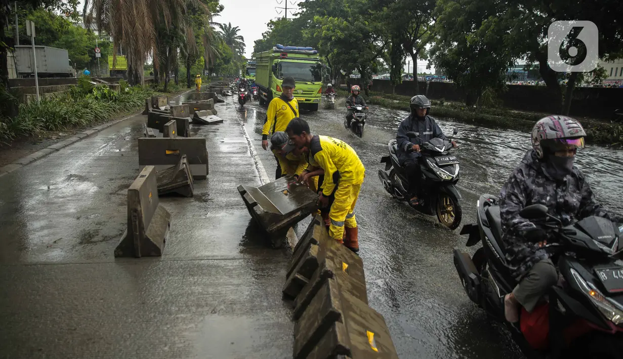 Petugas Sudin Bina Marga merapikan separator busway yang berserakan pascabanjir di Jalan Daan Mogot, Cengkareng, Jakarta, Jumat (3/1/2020). Separator busway tersebut berantakan akibat banjir yang menerjang sejak kemarin. (Liputan6.com/Faizal Fanani)