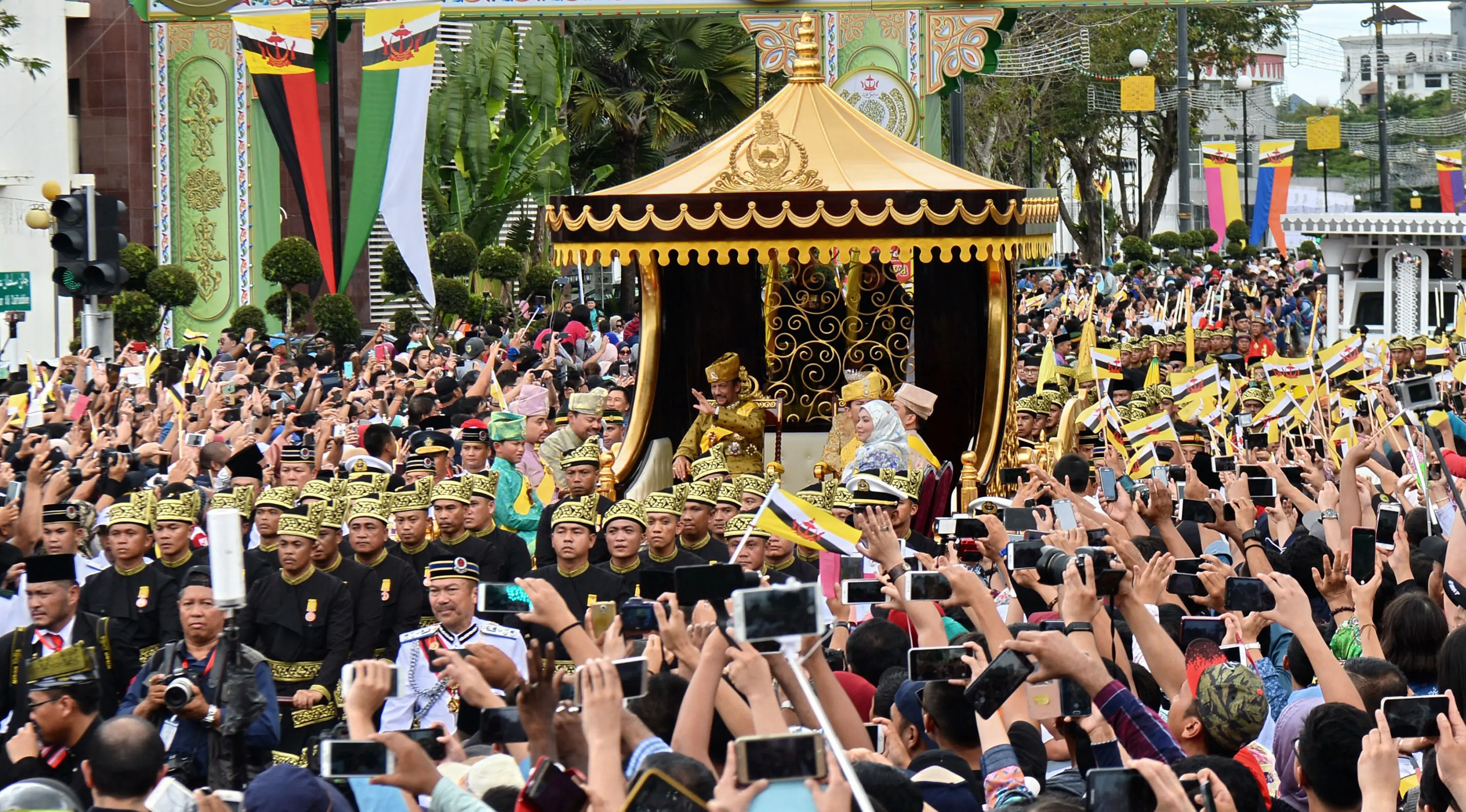 Ribuan warga mengabadikan moment kadatangan Sultan Hassanal Bolkiah dan Ratu Saleha Brunei pada prosesi Golden Jubileedi Bandar Seri Begawan (5/10). Perayaan tersebut menandai 50 tahun bertahta. (AFP PHOTO / Roslan Rahman)