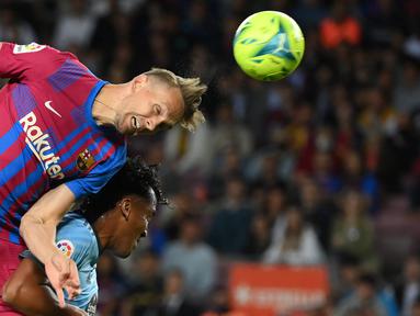 Pemain depan Barcelona, Luuk de Jong (kiri) berebut bola dengan bek Celta Vigo Joseph Aidoo pada laga lanjutan La Liga di Camp Nou, Rabu (11/5/2022) dini hari WIB. Barcelona menghajar Celta Vigo 3-1 di kandang sendiri. (LLUIS GENE / AFP)