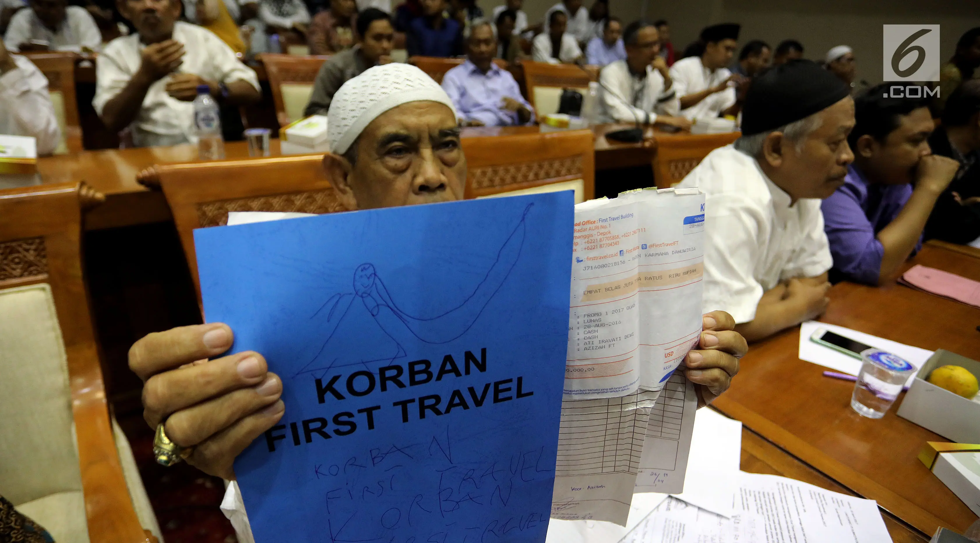 Calon jemaah umrah First Travel menunjukkan kwitansi saat mendatangi gedung DPR bertemu dan mengadu ke Komisi VIII DPR Fraksi PPP, di Kompleks Parlemen, Senayan, Jakarta, Jumat (18/8). (Liputan6.com/Johan Tallo)