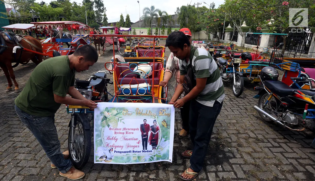 Sejumlah pria memasang spanduk di betor (becak motor) untuk persiapan arak-arakan ngunduh mantu Kahiyang-Bobby di Medan, Rabu (22/11). Ada 37 betor yang akan mengikuti pawai. (Liputan6.com/Johan Tallo)