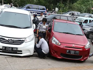 Petugas menderek dan menggembosi ban mobil yang parkir sembarangan di kawasan Tebet, Jakarta, Kamis (28/3). Meskipun berulang kali ditertibakan, namun masih banyak pengendara yang nekat parkir sembarangan sehingga mengganggu arus lalu lintas. (Liputan6.com/Immanuel Antonius)