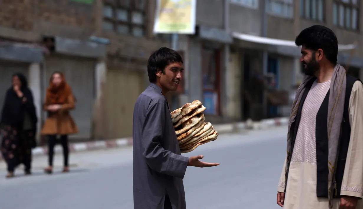 Seorang pria membawa roti gratis dari kota selama lockdown untuk mencegah penyebaran virus corona, pada bulan suci Ramadan di Kabul, Afghanistan (4/5/2020). Muslim di seluruh dunia sedang menjalankan Ramadan, ketika mereka menahan diri dari makan, minum dari subuh hingga senja. (AP/Rahmat Gul)