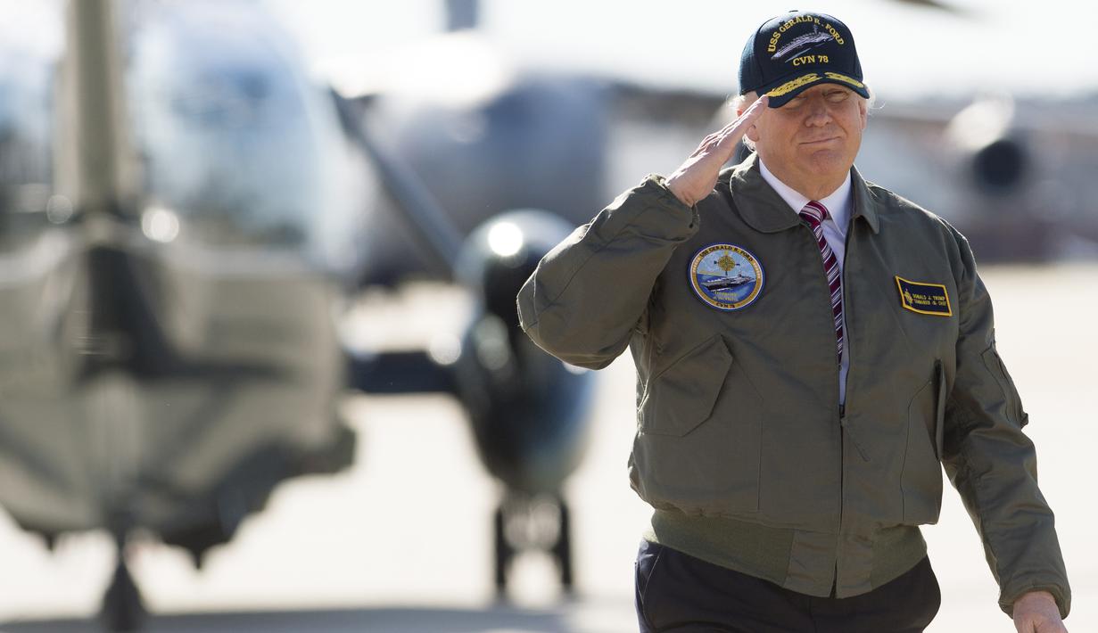 Presiden AS, Donald Trump memberi hormat saat berjalan menuju pesawat Air Force One sebelum berangkat dari Pangkalan Udara Langley di Virginia, (2/3). Trump tampak gagah mengenakan jaket panglima tertinggi Navy Seal. (AFP Photo / Saul Loeb)