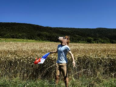 Seorang penonton memakai topeng kuda saat menyambut pebalap di Etape 15 Tour de France antara Bourg-en-Bresse dan Culoz, (17/7/2016). (AFP/Jeff Pachoud)