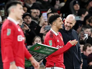 Pelatih Manchester United, Erik ten Hag, berbincang dengan Jadon Sancho saat melawan Nottingham Forest pada leg kedua babak semifinal Carabao Cup, di Stadion Old Trafford, Jumat (2/2/2023). Jadon Sancho kembali bermain untuk Manchester United setelah cukup lama hilang. (AFP/Paul Ellis)