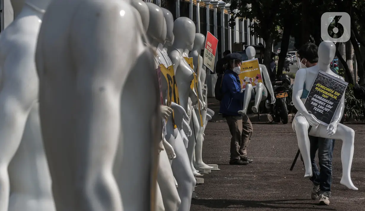 Aktivis Greenpeace Indonesia menata puluhan maneken saat menggelar aksi damai di depan gerbang kompleks DPR, Jakarta Pusat, Senin (29/6/2020). Aksi tersebut dilakukan sebagai bentuk penolakan terhadap RUU Omnibus Law. (Liputan6.com/Johan Tallo)