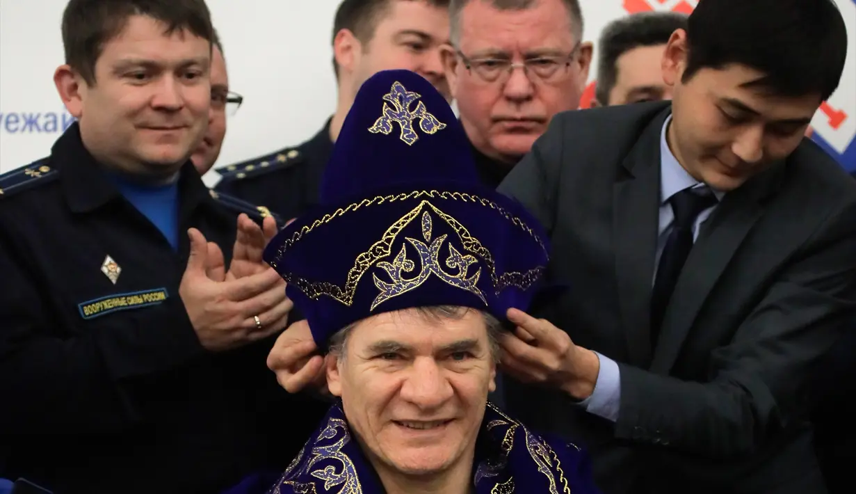 Pejabat kota Karaganda memakaikan kostum nasional Kazakh pada astronot Italia Paolo Nespoli dalam upacara penymabutan di bandara Karaganda, Kazakhstan (14/12). (AP/ Dmitri Lovetsky/Pool)