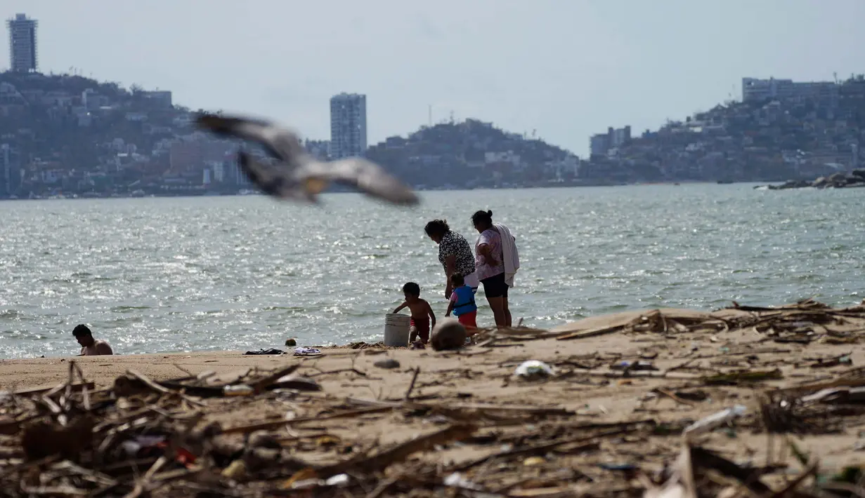 Warga setempat berjalan di pantai yang dipenuhi puing-puing setelah Badai Otis menerjang Acapulco, Meksiko, Kamis, 26 Oktober 2023. (AP Photo/Marco Ugarte)