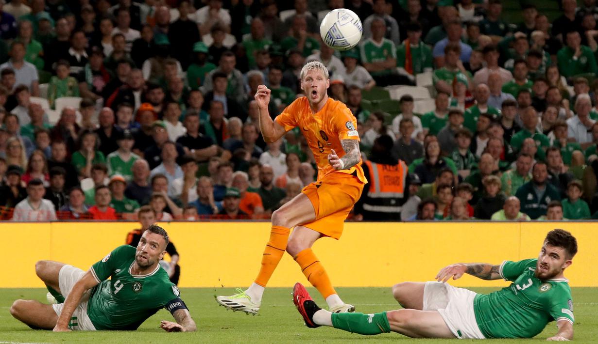 Pemain Timnas Belanda, Wout Weghorst (tengah), berhasil mengelabui dua pemain Timnas Irlandia Adam Idah (kiri) dan Ryan Manning dalam pertandingan grup B Kualifikasi Euro 2024 yang berlangsung di Aviva Stadium, Dublin, Senin (11/9/2023) dini hari WIB. (AFP/Paul Faith)