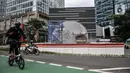 Pesepeda saat melintas di depan proyek pembangunan Tugu Sepeda di Jalan Jenderal Sudirman, Jakarta, Senin (5/4/2021). Pembangunan tugu ini berbentuk satu buah ban sepeda berukuran raksasa. (merdeka.com/Iqbal S. Nugroho)