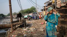 Seorang wanita marapikan kain dikepalanya ketika dia berjalan di dekat saluran pembuangan air limbah yang dipenuhi sampah di lingkungan berpenghasilan rendah di New Delhi, India (4/10/2019). (AFP Photo/Noemi Cassanelli)