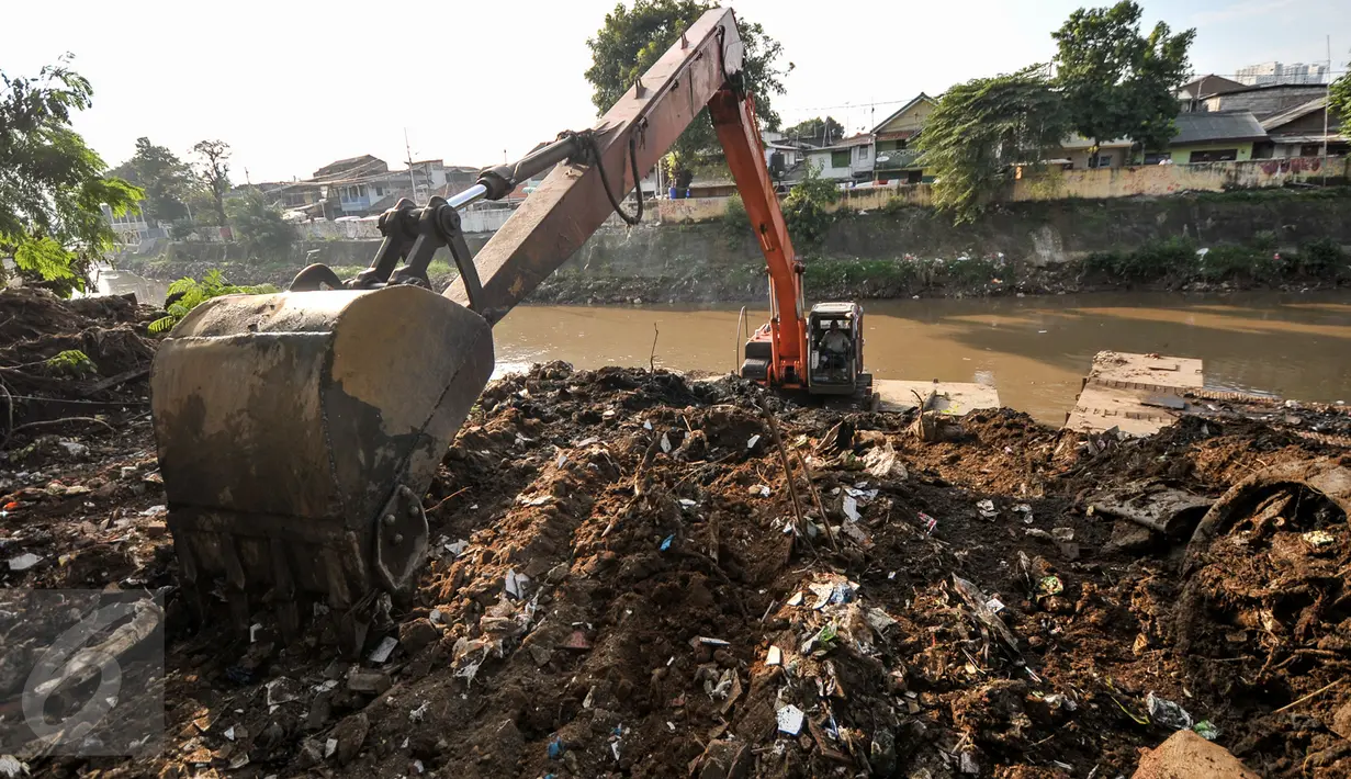 Alat berat melakukan pengerukan tumpukan sisa lumpur dan tanah yang menumpuk di pinggir kali Ciliwung, Jakarta, Kamis (28/7). Tumpukan tanah dan lumpur sisa dari pengerukan kali Ciliwung mulai dibersihkan.(Liputan6.com/Yoppy Renato)