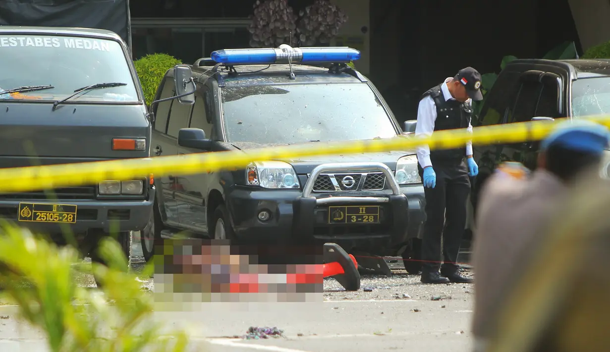 Polisi memeriksa jenazah seorang yang diduga sebagai pelaku bom bunuh diri di Mapolrestabes Medan, Sumatera Utara, Rabu (13/11/2019). Satu orang terduga pelaku bom bunuh diri tewas di lokasi kejadian. (ATAR/AFP)