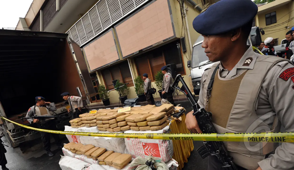 Sejumlah petugas kepolisian mengamankan barang bukti narkoba jenis ganja dan mobil tronton box sebesar dua ton hasil penangkapan ganja Aceh di Polres Jakarta Barat, Jumat (13/2/2015). (Liputan6.com/Faizal Fanani)