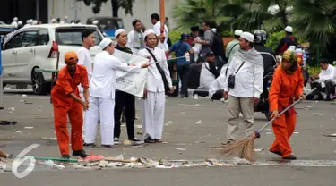 Petugas kebersihan DKI Jakarta membersihkan ceceran sampah di Silang Tenggara Monas, Jakarta, Jumat (14/10). Sebelumnya, ribuan massa ormas berunjuk rasa mendesak mundur Gubernur DKI Jakarta, Basuki Tjahaja Purnama. (Liputan6.com/Helmi Fithriansyah)