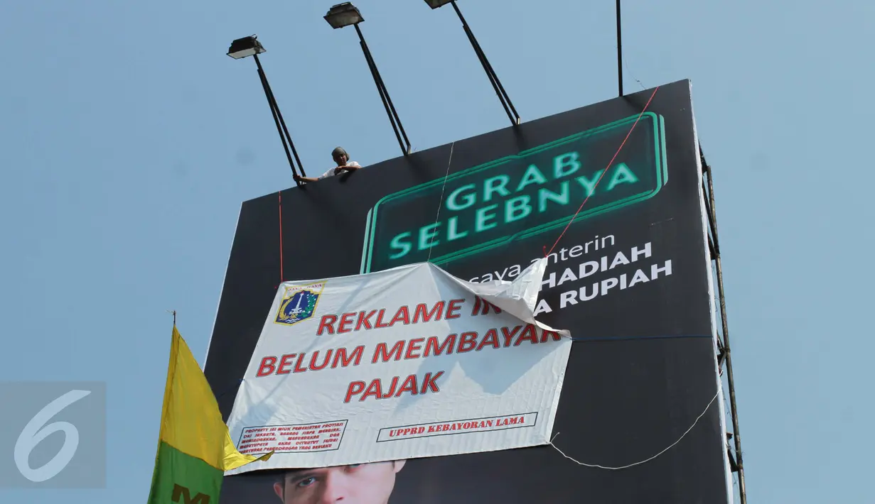 Petugas memasang spanduk bertuliskan "Reklame Ini Belum Bayar Pajak" di Kawasan Kebayoran Lama, Jakarta, Kamis (23/2). Razia oleh Satpol PP dan Dinas BP2T tersebut menertibkan reklame yang tidak membayar pajak. (Liputan6.com/Gempur M Surya)